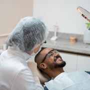 Man in dentist chair looking at teeth in mirror