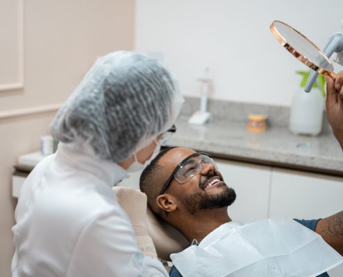 Man in dentist chair looking at teeth in mirror